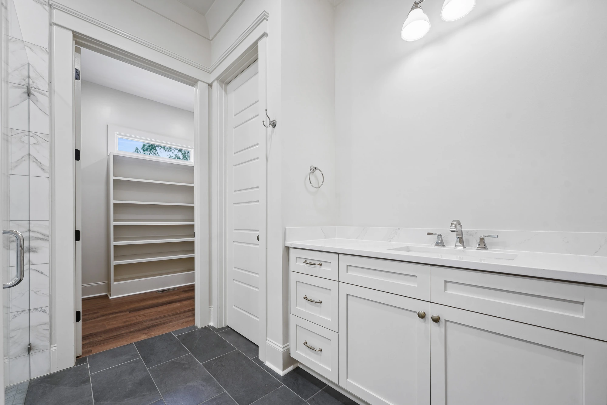 Bathroom vanity leading into walk-in closet in Holly Springs custom home